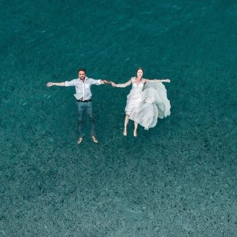 Couple de jeunes mariés qui flottent sur l'eau de mer en tenue de mariage mariage